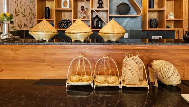 A reception area with a wooden counter, wicker baskets, and shelves with various decorative items. - Bloom Hotel - Golf Course Road, Sector 43 (Gurugram)