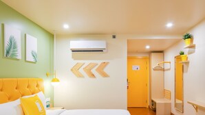 A hotel room with a large bed, a bedside table, a lamp, a mirror, and a door leading to a bathroom. - Bloom Hotel - Golf Course Road, Sector 43 (Gurugram)