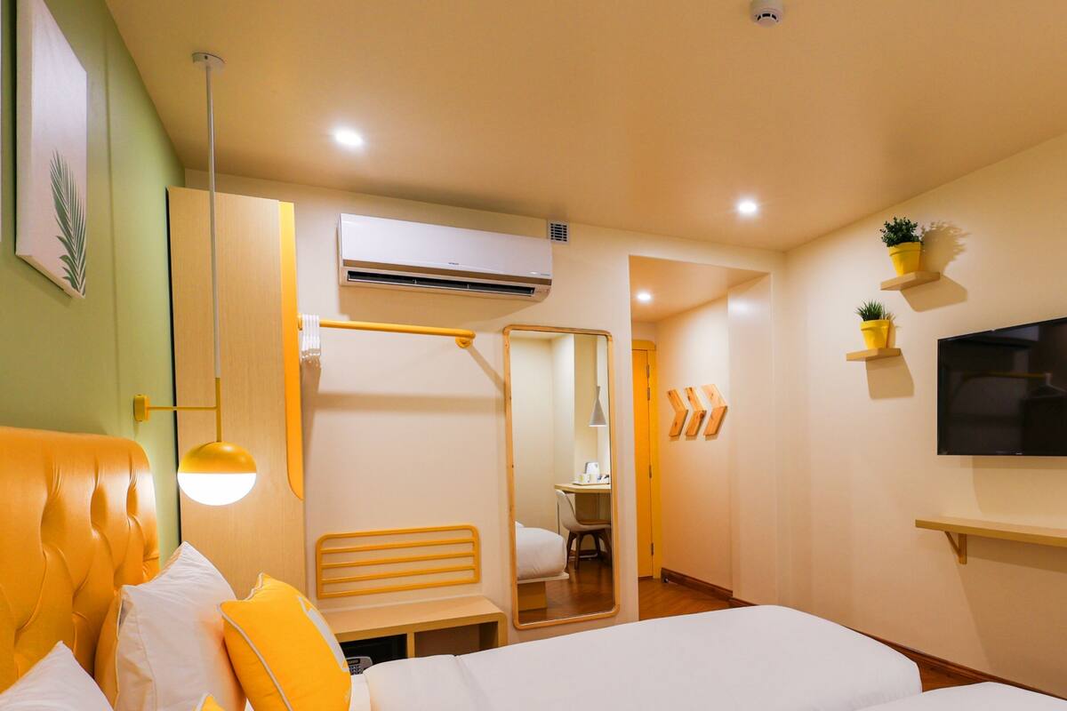 A hotel room with a bed, bedside table, and a TV on the wall.
