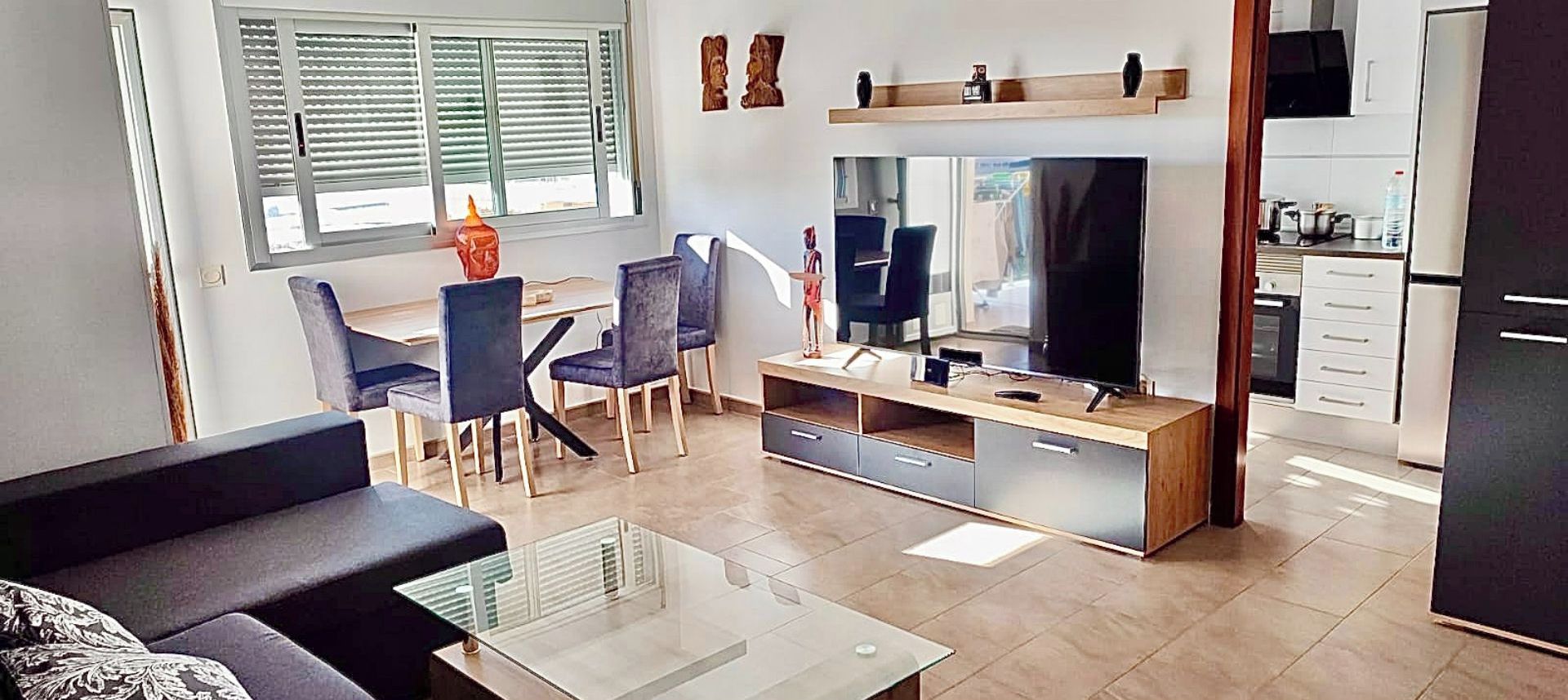 Ein modernes Wohnzimmer mit Fernseher, Sofa und Essbereich.