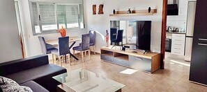 A modern living room with a TV, sofa, and dining area.