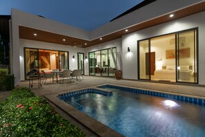 A modern house with a swimming pool, a dining area, and a bedroom with a large window. - Oriental 3br Pool Villa (Rawai)
