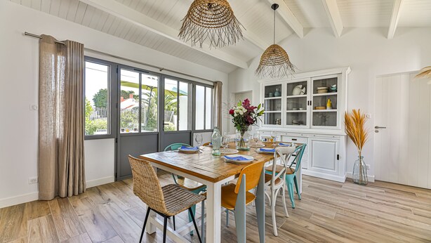 A dining area with a wooden table set for four, surrounded by wicker chairs. - Noirmoutier-le vieil Charming house with enclosed garden 300m from the beach (Noirmoutier-en-l'Île)