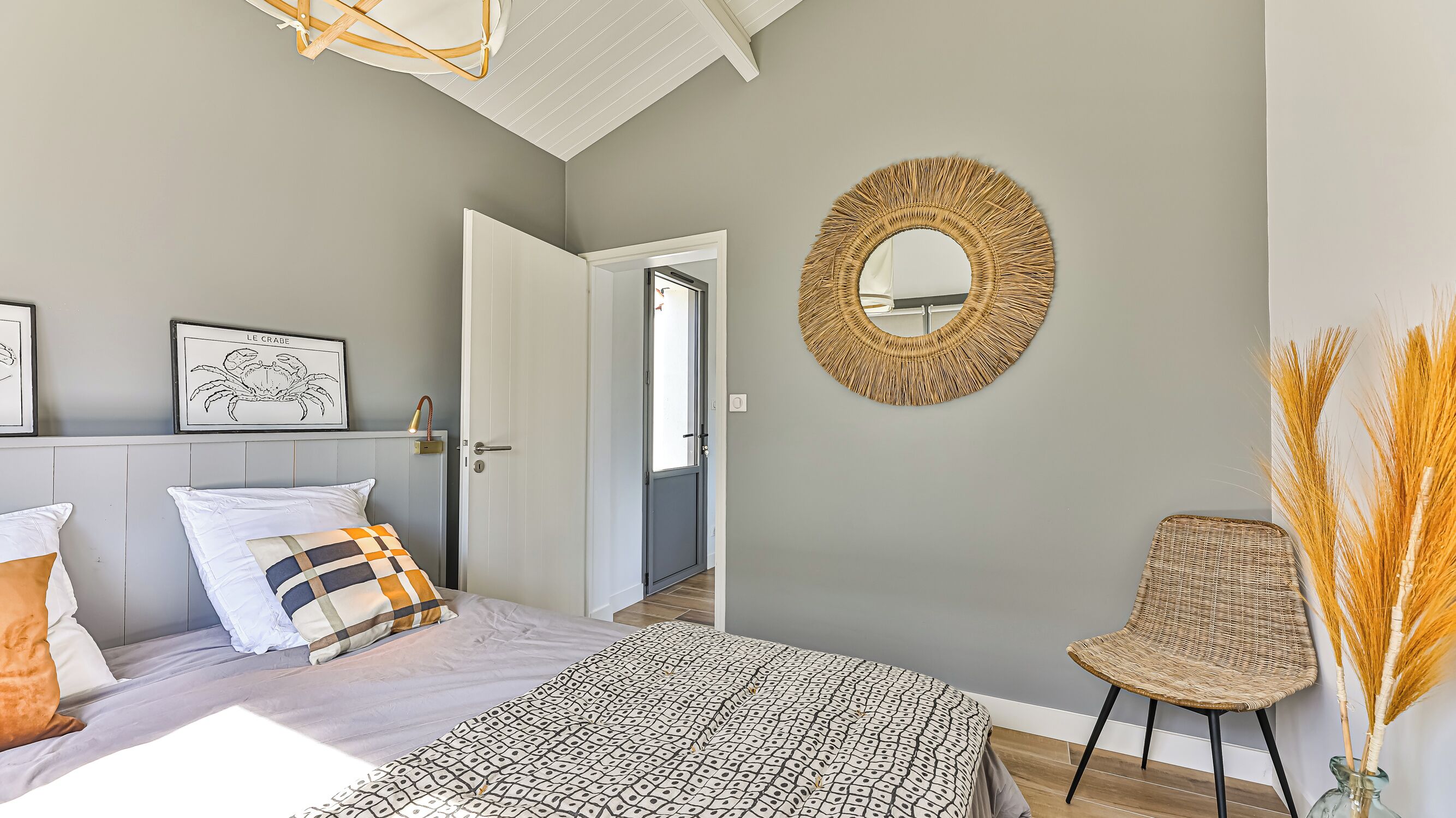 Ein Schlafzimmer mit einem Bett, einem Sessel, einem Spiegel und einer Tür zu einem anderen Raum.