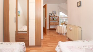 Een slaapkamer met een houten garderobe, een nachtkastje, een klein raam en een radiator.