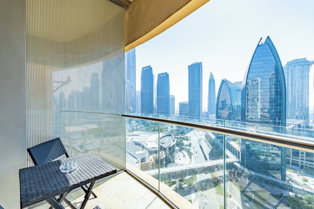 Ein Balkon mit Glasgeländer und Blick auf eine Skyline mit modernen Wolkenkratzern.