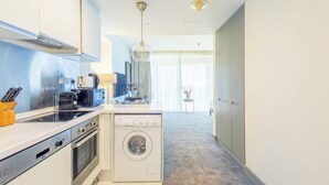 Een moderne keuken met een ingebouwde oven, magnetron en vaatwasser. Er is een spoelbak met kraan, een aanrecht met messenblok en een hangende lamp.