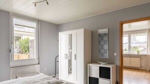 A bedroom with a bed, wardrobe, bedside table, and a view of the outside. - Garden Retreat With Pond View (Neumagen-Dhron)