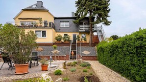 A two-story house with a balcony, a garden with various plants and a gravel pathway. - Garden Retreat With Pond View (Neumagen-Dhron)