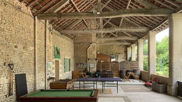 Un espace de loisirs abrité comprenant une table de billard, une table de baby-foot et une table de ping-pong.