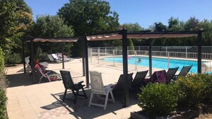 Un espace extérieur abrité comprenant une piscine, des chaises longues et une pergola.