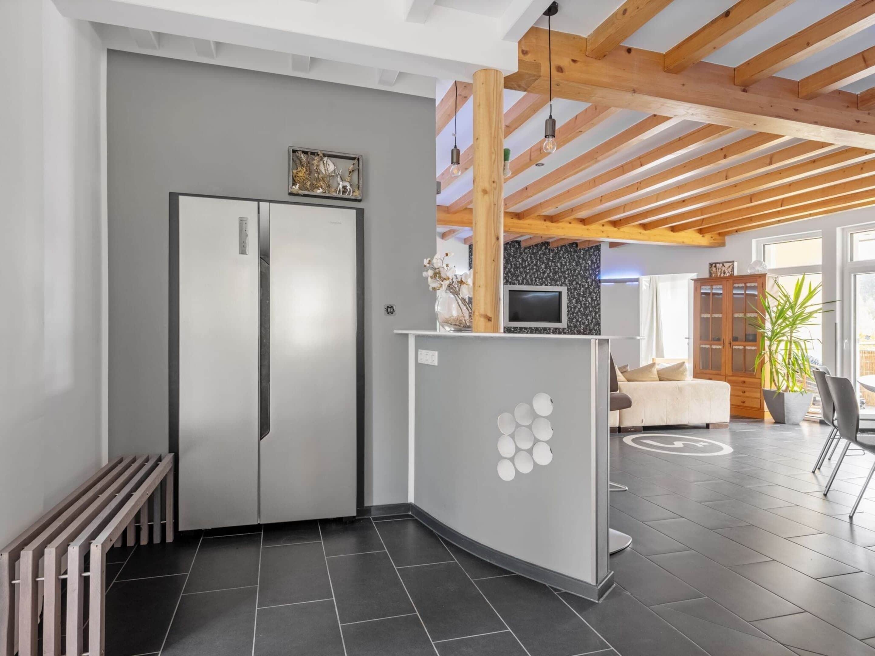 A modern kitchen with a built-in refrigerator, a curved counter, and a wooden ceiling structure.