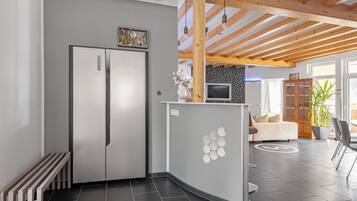 A modern kitchen with a built-in refrigerator, a curved counter, and a wooden ceiling structure.