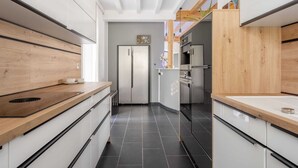 A modern kitchen with wooden countertops, stainless steel appliances, and a black tiled floor. - Co2-neutrale und Barrierefreie Ferienwohnung im Sauerland (Herscheid)