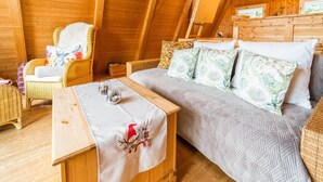 A cozy loft bedroom with a bed, a small table with glasses, and wicker furniture. - Gemutliches Waldversteck in Suhl (Suhl)