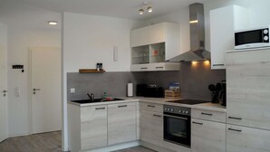Eine moderne Küche mit hellen Holzschränken, einem eingebauten Backofen und einer Mikrowelle.