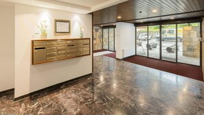 A modern lobby with a marble floor, a wall-mounted mailbox, and a framed document.