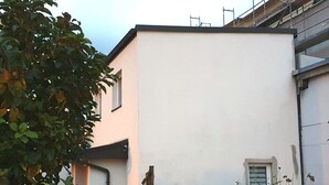 A building with a white facade, a small window, and a brick base.
