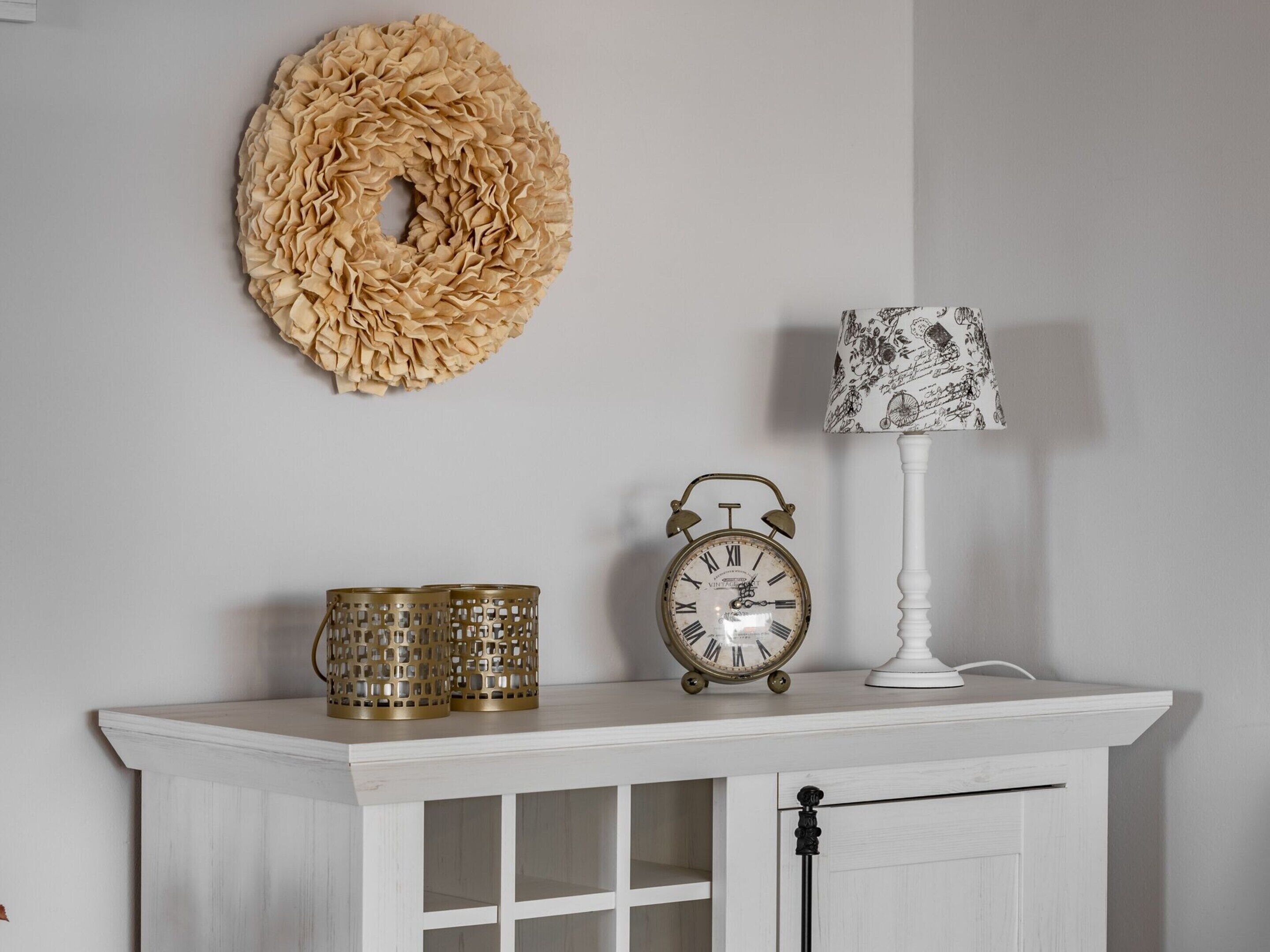 Een witte kast met een klok en decoratieve items bovenop.