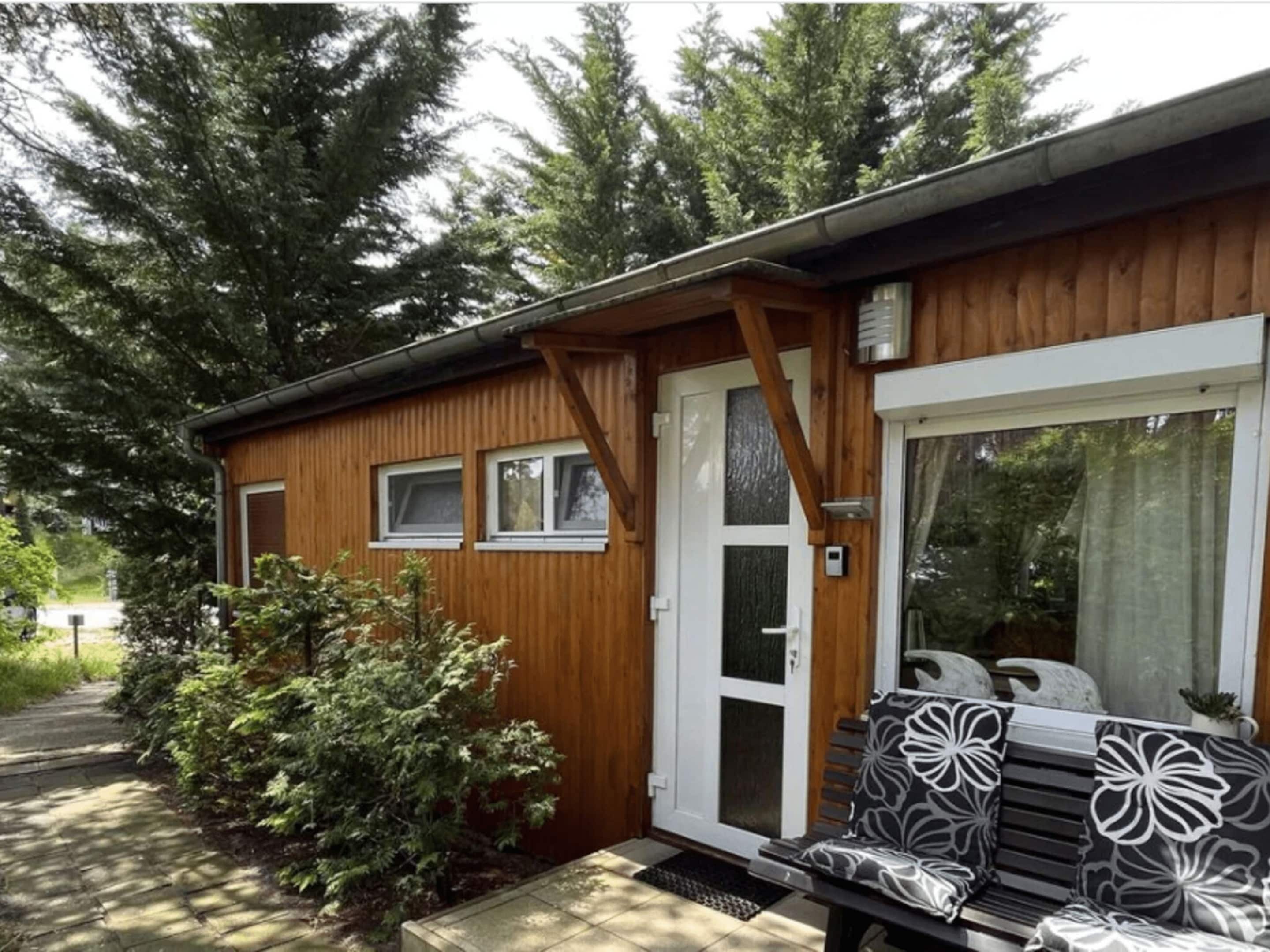A wooden cabin with a door, windows, and a bench outside.