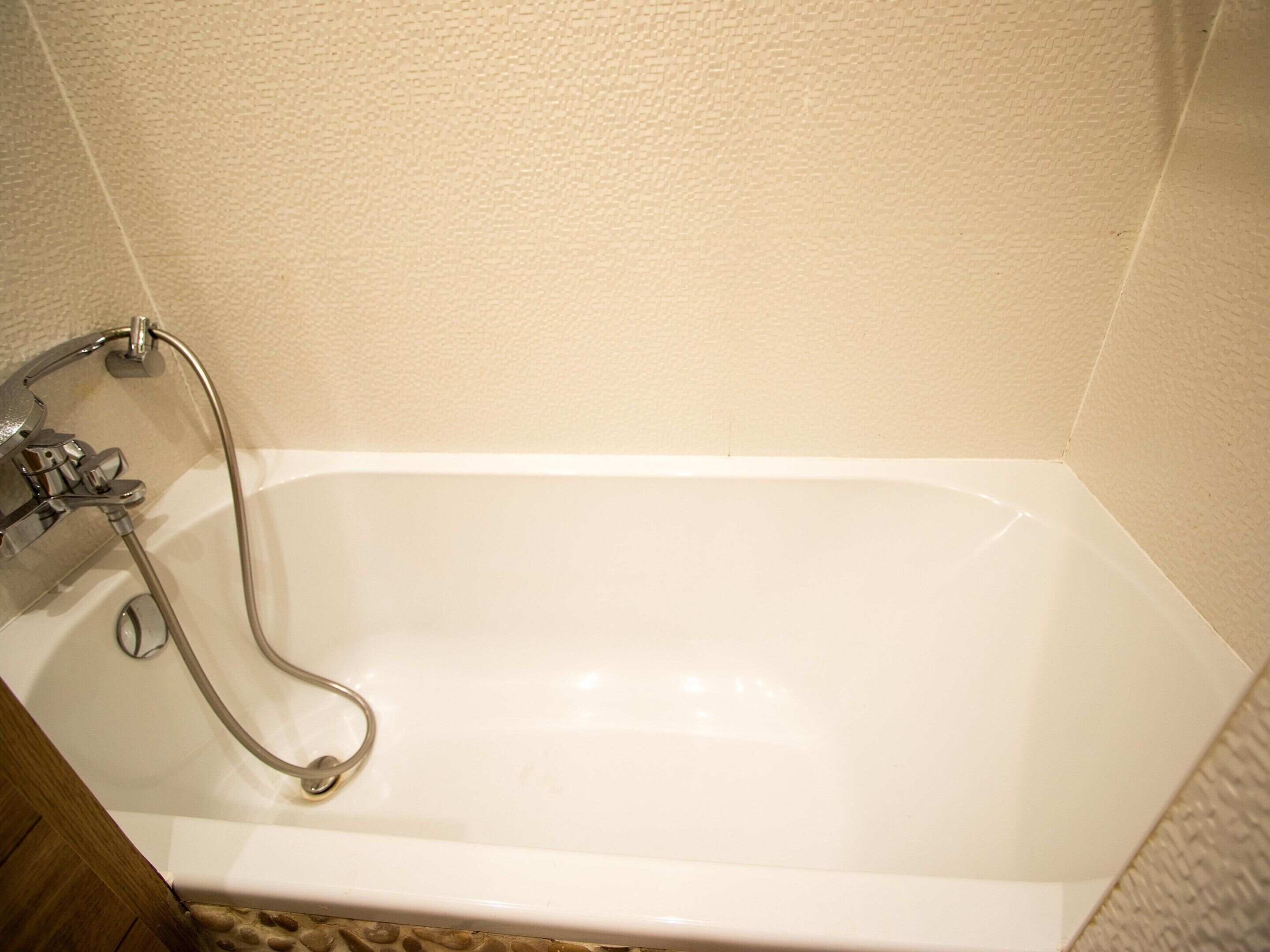 A white bathtub with a handheld showerhead and a faucet.