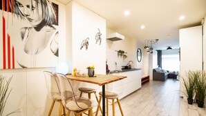 Una cocina moderna con una isla central, sillas traslúcidas y una mesa de comedor.