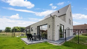 Moderni talo, jossa on patio, ruokailutila ja suuri lasiovi.