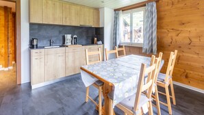 Une cuisine moderne avec des meubles en bois, une table à manger avec des chaises et une fenêtre avec des rideaux.