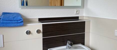 A bathroom with a white sink, a mirror above it, and a towel on the wall.