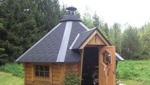 Eine kleine Holzhütte mit geneigtem Dach, einer Tür und einem Fenster.