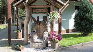 Eine Holzhütte mit einem Schild, auf dem "Jägersruh" steht, und einem geschnitzten Stuhl.