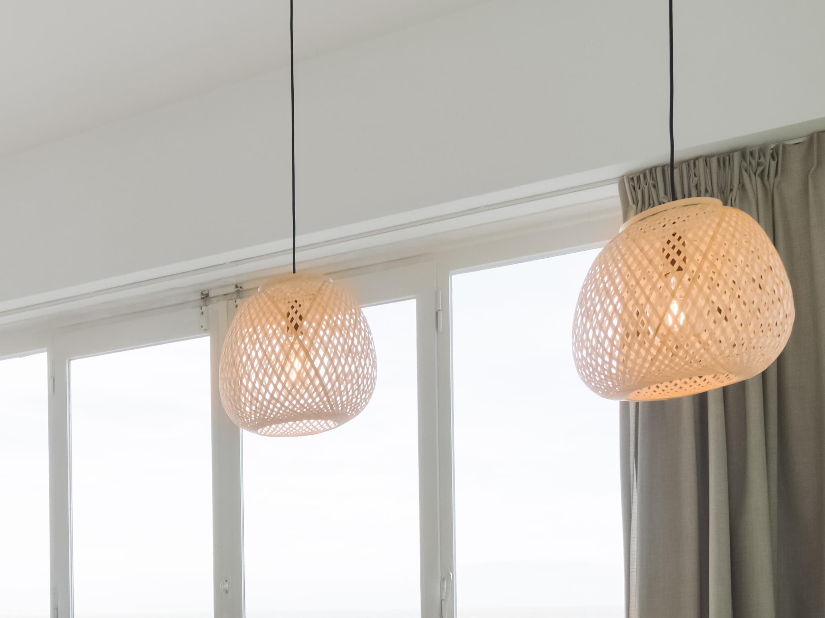 Quarto com duas luminárias suspensas de tecido e vista através de amplas janelas.