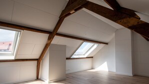 A spacious attic room with high ceilings, exposed wooden beams, and skylights. - Nice Holiday Home in Ostend by the sea With a Terrace (Ostend)