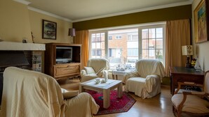 A living room with a fireplace, a television, and a view of the outside. - Nice Holiday Home in Ostend by the sea With a Terrace (Ostend)