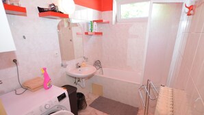 A compact bathroom with a washing machine, a sink, and a bathtub. - Cozy Apartment in Eastern Bohemia Near Town Center (Vysoke Myto)