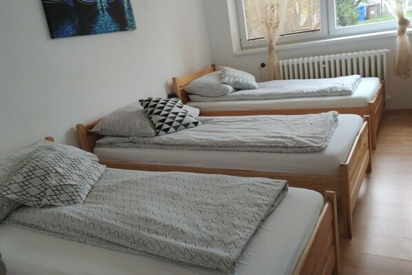 A room with three wooden beds, each with a patterned pillow and a blanket. - Cozy Apartment in Eastern Bohemia Near Town Center (Vysoke Myto)