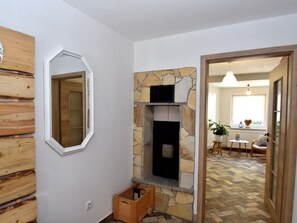 Cozy room with a stone fireplace, herringbone-patterned floor, and a view into another room.