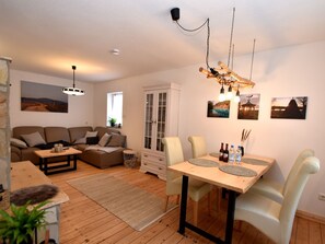 A cozy living room with a sofa set, a dining table with chairs, and a cabinet.
