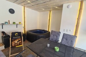 A room with a glass-top table, a black sofa with cushions, a round black seating area, and a poster on the wall.