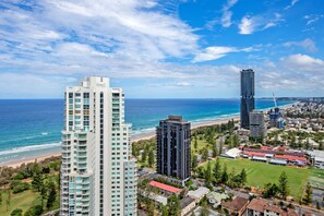 A high-rise hotel with multiple floors and balconies overlooking a beach and ocean.