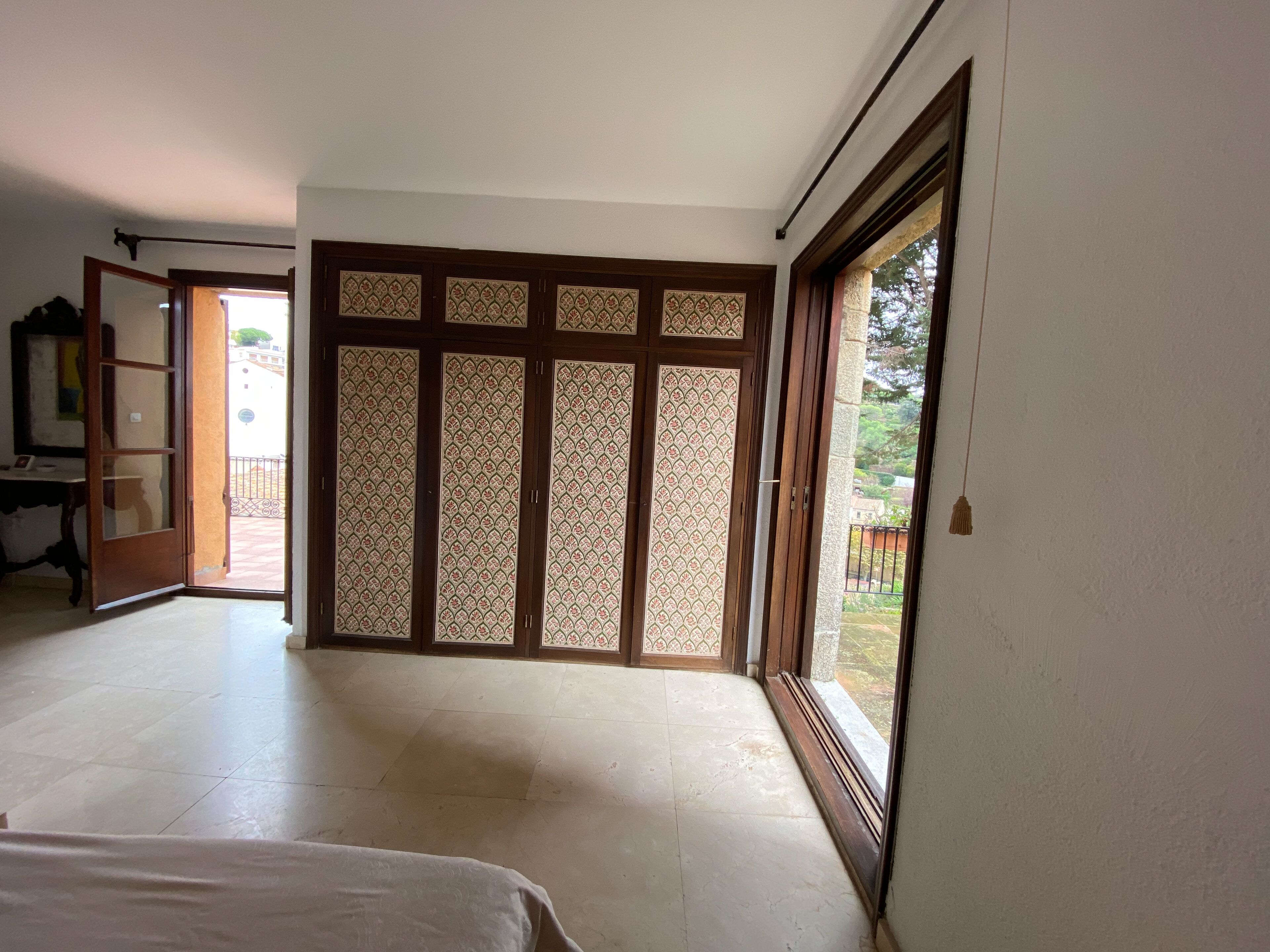 A room with a large sliding door with intricate patterns, a bed, and a view of a courtyard.