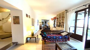 Un salon avec un canapé, une table basse, une lampe, une bibliothèque et un escalier.