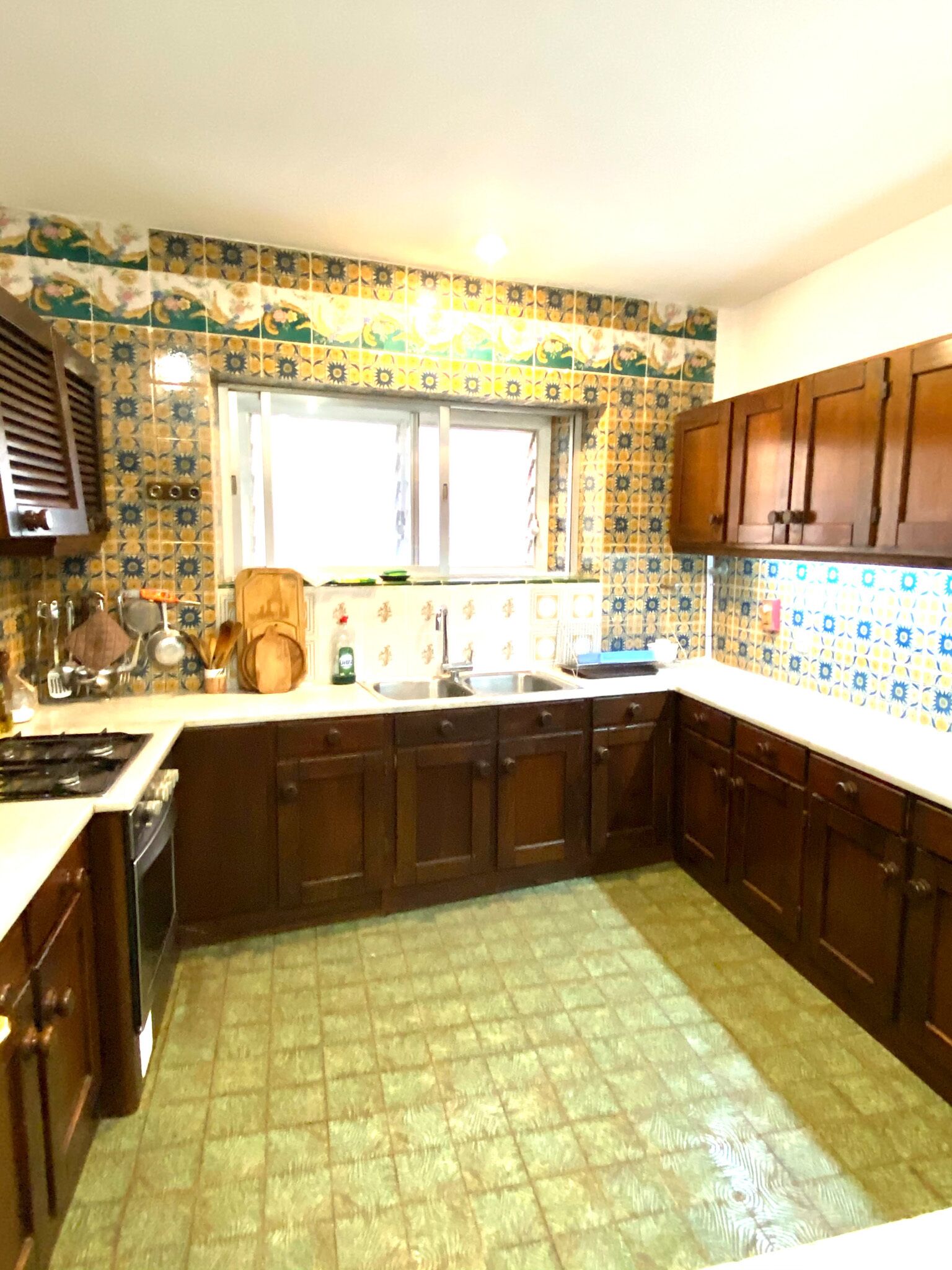 Una cocina con baldosas estampadas, armarios de madera, una ventana y una estufa.
