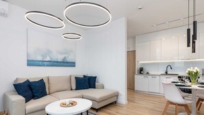 A modern living room with a sofa, coffee table, and dining area with chairs.