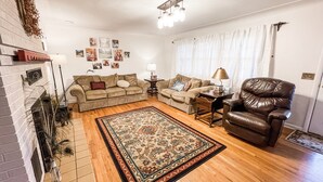 A living room with a fireplace, two sofas, a coffee table, a rug, and a leather armchair. - The Ranch House (Flippin)