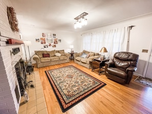 A living room with a fireplace, two sofas, a coffee table, a rug, and a leather armchair.
