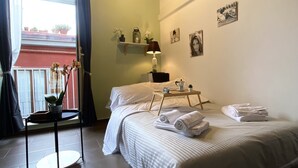 Une chambre à coucher avec un lit, une table de chevet avec une lampe, une fenêtre avec des rideaux et une vue sur l’extérieur.