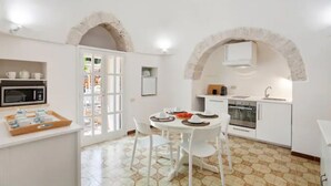 Une cuisine avec des meubles blancs, un four à micro-ondes et une table à manger avec des chaises.