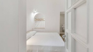Une chambre à coucher avec un lit, un luminaire fixé au mur et une porte.