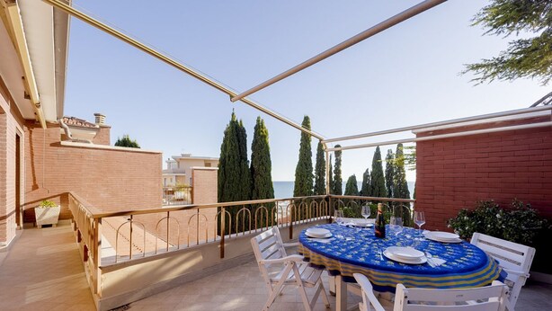 A round table with chairs on an outdoor patio with a view of the sea. - GuestHost - Cozy penthouse of 110 sqm, able to accommodate up to 4 people, located on the fourth floor of a building with elevator and private garage.The apartment boasts an enchanting view of the sea and Portosole, surrounded by Villa Ormond's and Villa (Sanremo)